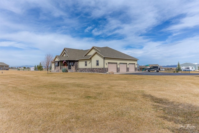 2160 Crested Wheat Loop, East Helena, MT 59635 - view of side of home with a yard, a porch, stone siding, an attached garage, and driveway