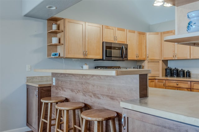 675 Pebble Dr, Kalispell, MT 59901 - kitchen featuring stainless steel microwave, light brown cabinetry, light countertops, open shelves, and vaulted ceiling