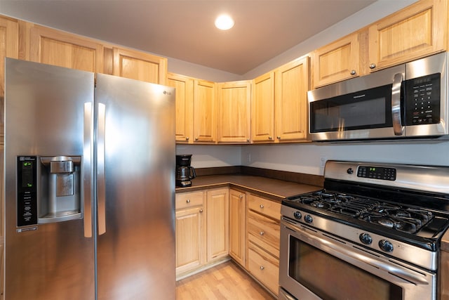 100 Forest Ridge Dr Unit B, Whitefish, MT 59937 - kitchen featuring appliances with stainless steel finishes, light brown cabinets, dark countertops, and light wood finished floors