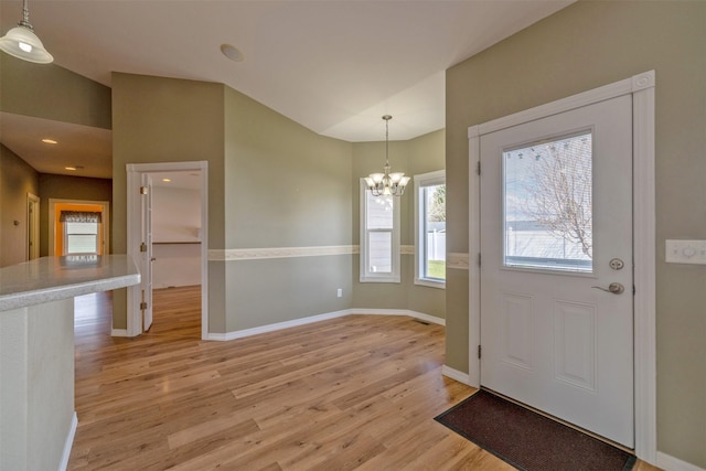 entrance foyer featuring light wood-style flooring, baseboards, plenty of natural light, and an inviting chandelier