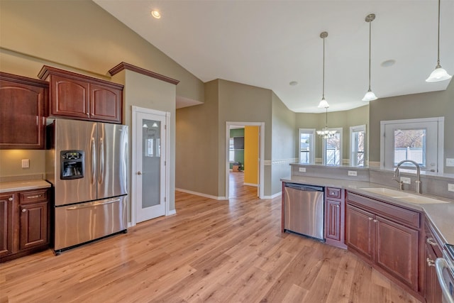 kitchen featuring a sink, light wood-type flooring, appliances with stainless steel finishes, light countertops, and a notable chandelier