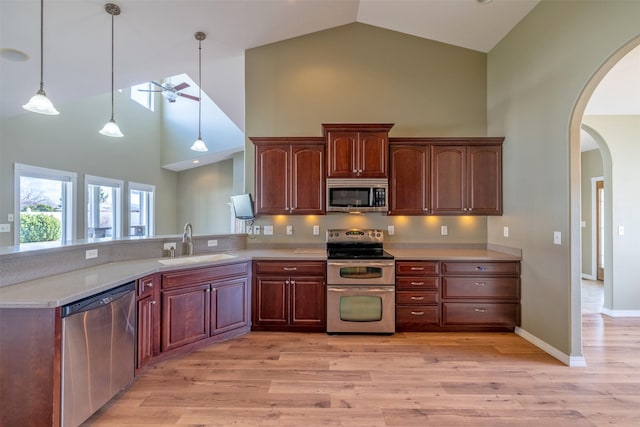 kitchen with stainless steel appliances, arched walkways, a sink, and high vaulted ceiling