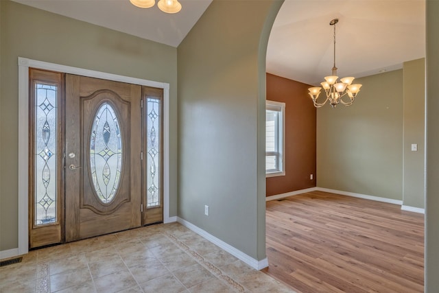 entryway with a chandelier, arched walkways, a wealth of natural light, and baseboards