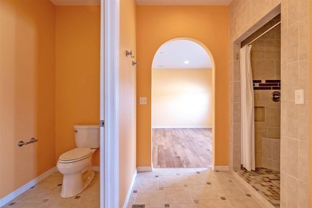 bathroom featuring toilet, tile patterned flooring, and tiled shower