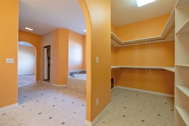 walk in closet with arched walkways and tile patterned flooring