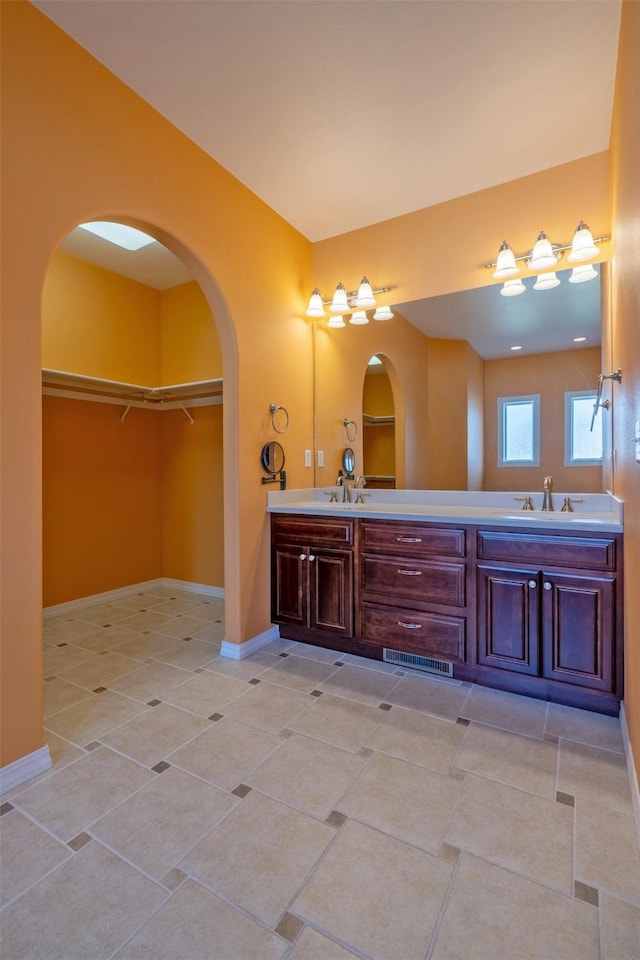bathroom featuring a spacious closet, tile patterned floors, a sink, and double vanity