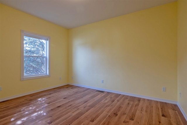 unfurnished room featuring visible vents, light wood finished floors, and baseboards
