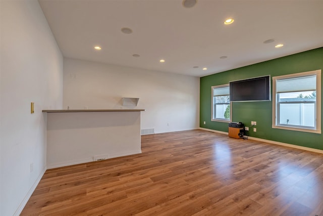 unfurnished living room featuring baseboards, wood finished floors, visible vents, and recessed lighting