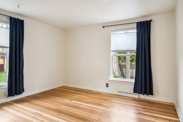 unfurnished room with baseboard heating, baseboards, and hardwood / wood-style flooring