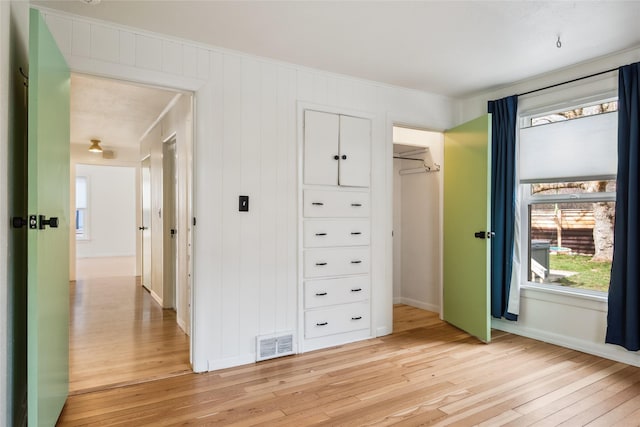 unfurnished bedroom with light wood-type flooring, a closet, and visible vents