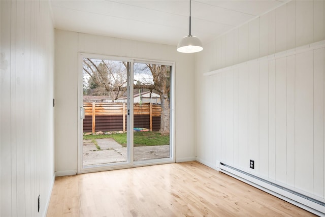 unfurnished dining area featuring baseboard heating, wood finished floors, and baseboards