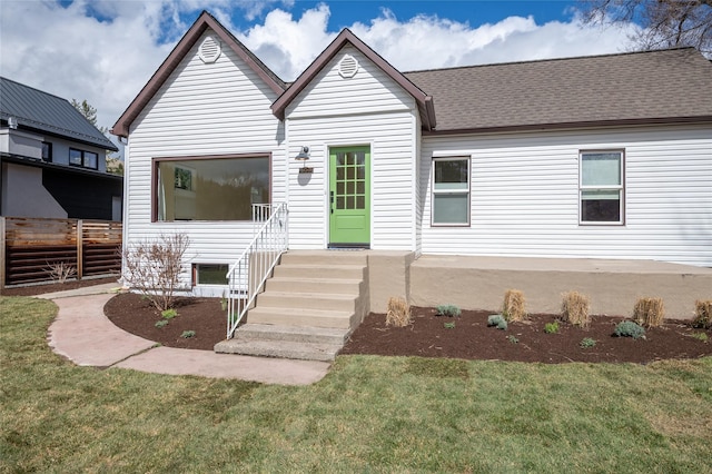 view of front of home with roof with shingles and a front lawn