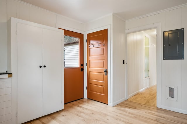 entryway with crown molding, light wood-style floors, and electric panel