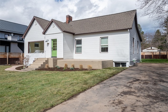 view of front of property featuring a chimney, a shingled roof, a front yard, and fence