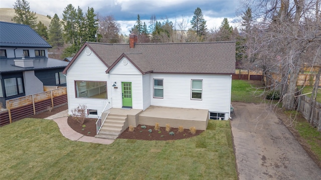 view of front of property featuring a front yard, a patio, fence, and a shingled roof