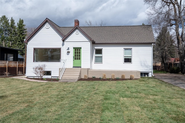view of front of home with a chimney, a shingled roof, and a front yard