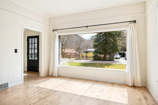 doorway to outside featuring ornamental molding, visible vents, baseboards, and wood finished floors