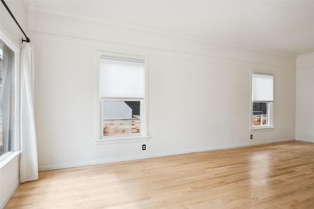 unfurnished room with crown molding, light wood finished floors, and baseboards