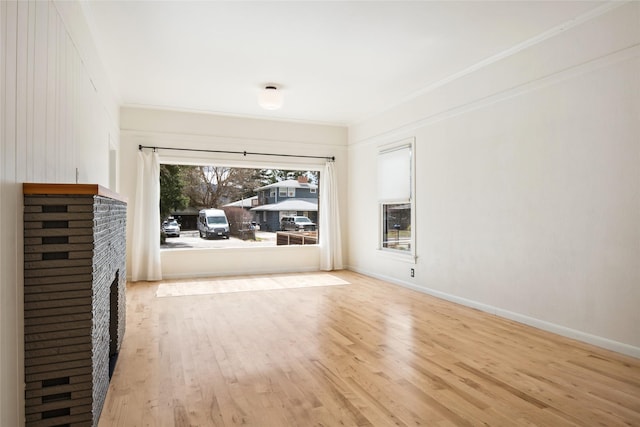 unfurnished living room with crown molding, wood finished floors, and baseboards