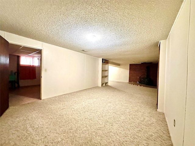 carpeted spare room featuring a wood stove and a textured ceiling