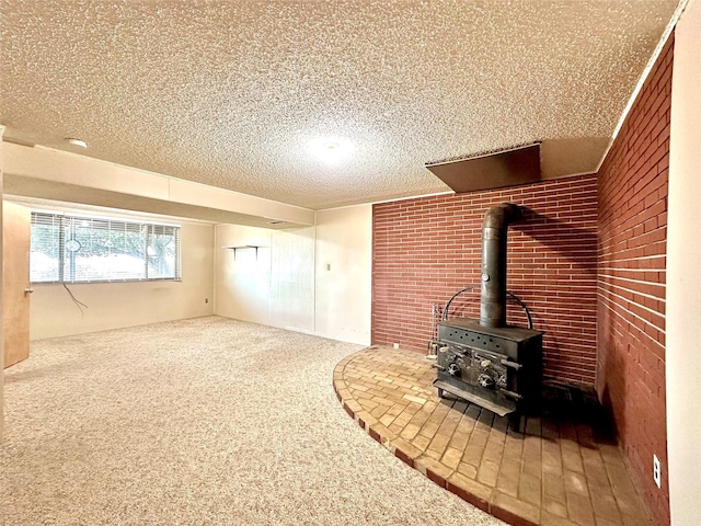 unfurnished living room with a textured ceiling, brick wall, carpet flooring, and a wood stove