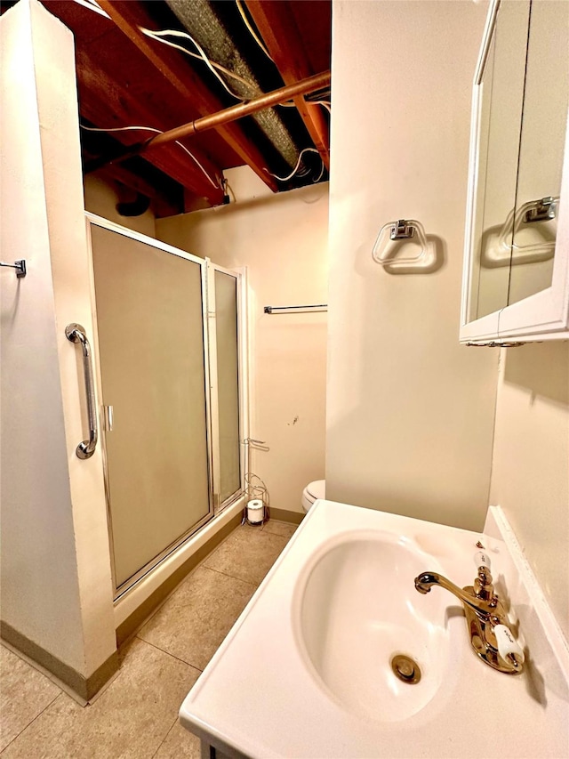 bathroom with baseboards, toilet, vanity, tile patterned flooring, and a stall shower