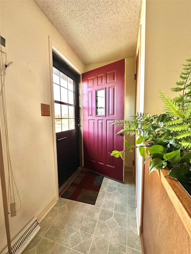 doorway to outside with visible vents, a textured ceiling, and baseboards