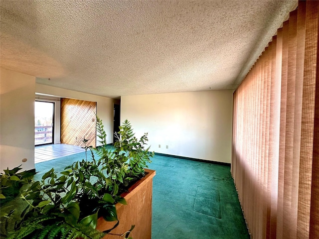 interior space with carpet flooring, a textured ceiling, and baseboards