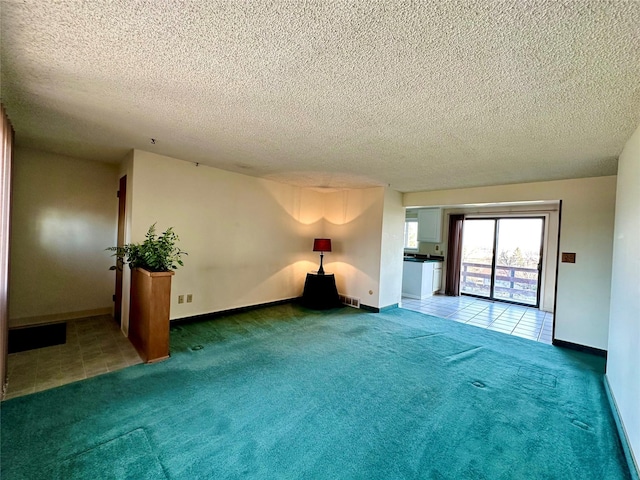 empty room with tile patterned floors, visible vents, carpet, and a textured ceiling