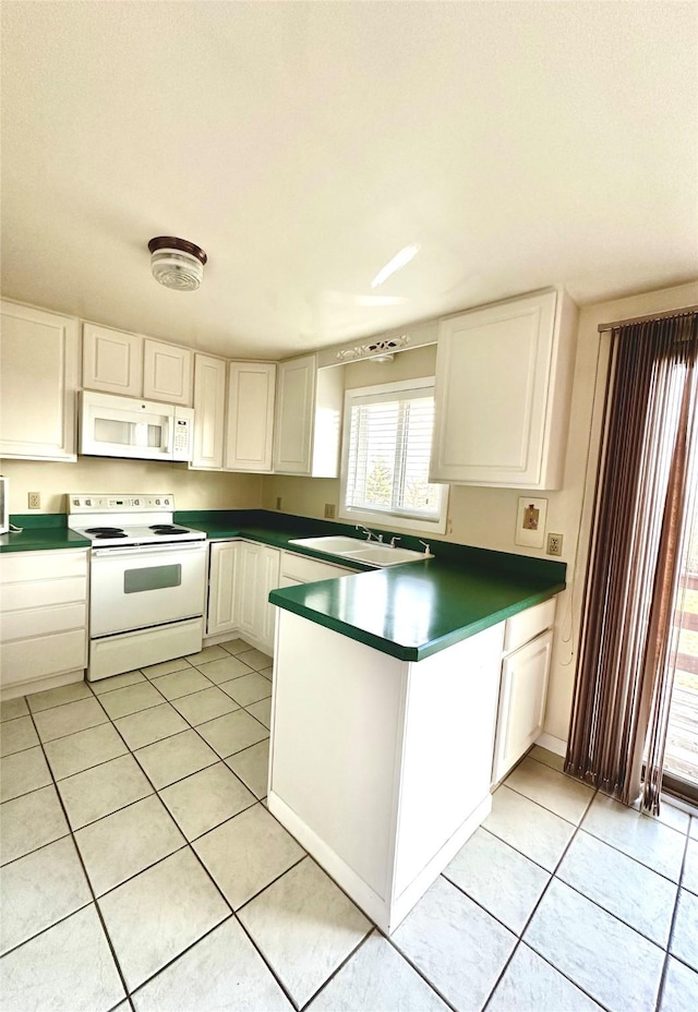 kitchen with light tile patterned floors, a sink, white appliances, a peninsula, and white cabinetry