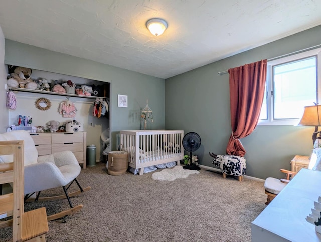 carpeted bedroom featuring baseboards and a crib
