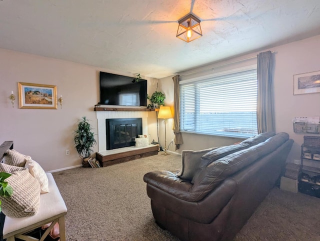 carpeted living room featuring baseboards and a glass covered fireplace