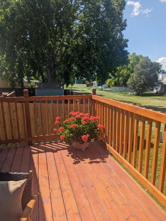 wooden deck featuring a shed, an outbuilding, and a lawn