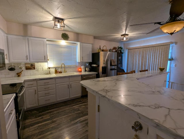 kitchen with tasteful backsplash, white cabinetry, appliances with stainless steel finishes, dark wood-style flooring, and a sink