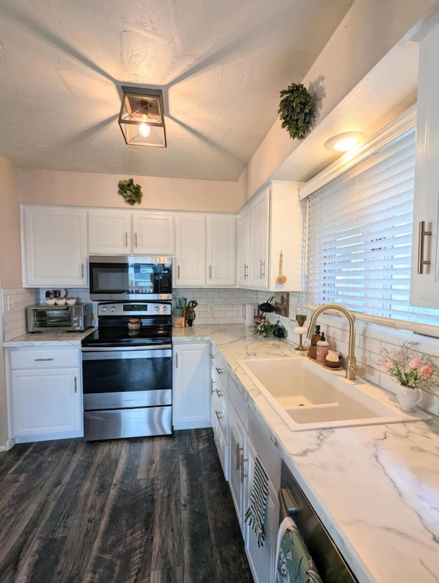 kitchen with a sink, white cabinets, tasteful backsplash, and stainless steel appliances