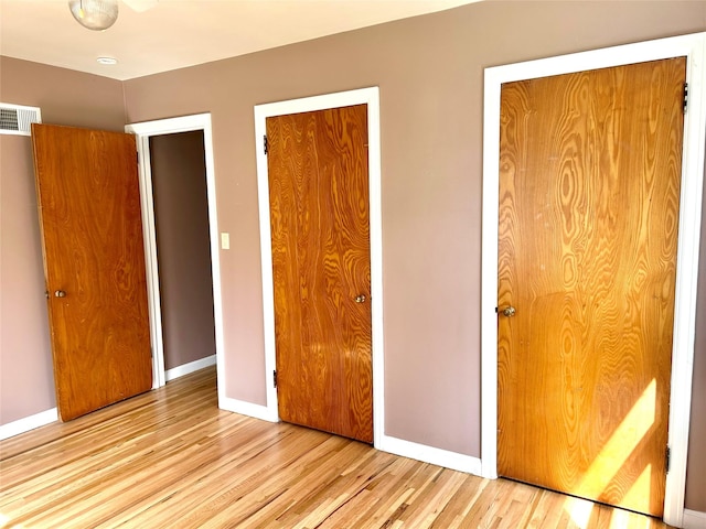 unfurnished bedroom featuring visible vents, wood finished floors, and baseboards