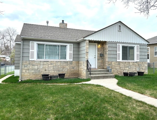 view of front of property with fence, a chimney, a front lawn, and stone siding