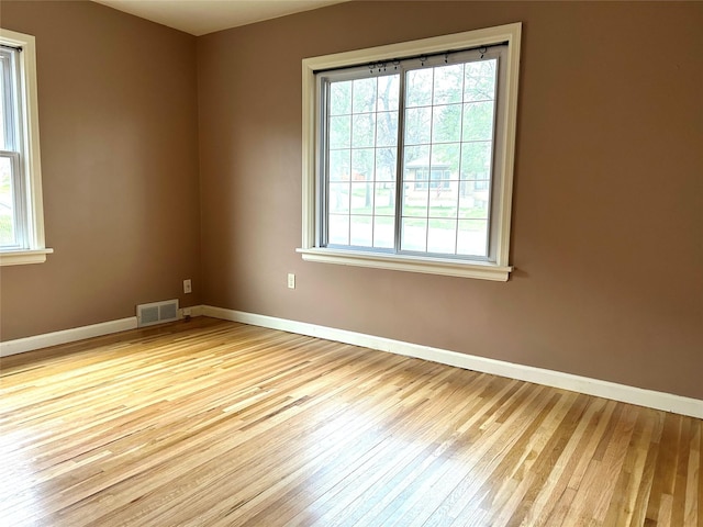 unfurnished room featuring baseboards, visible vents, and wood finished floors