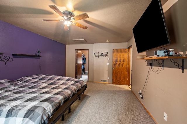 bedroom featuring a closet, a textured ceiling, a ceiling fan, a walk in closet, and light colored carpet