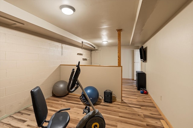 workout room with light wood-style floors, baseboards, and concrete block wall