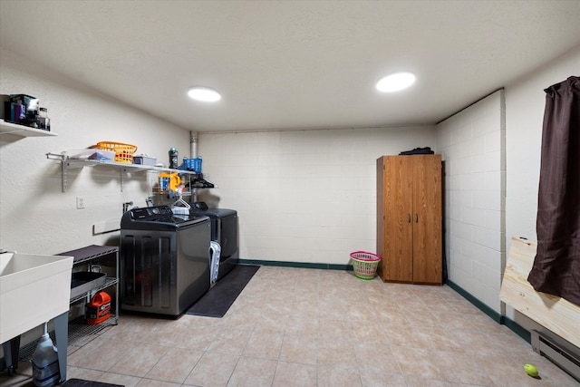 laundry room with washing machine and dryer, laundry area, a baseboard radiator, a sink, and concrete block wall