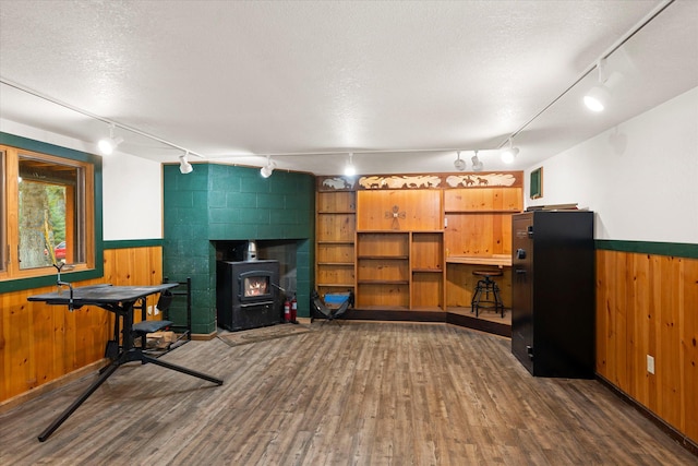 interior space with a wood stove, wainscoting, wood finished floors, and track lighting