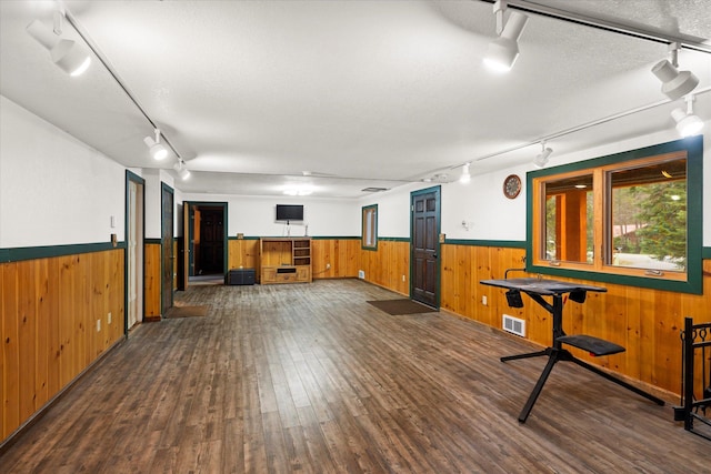 interior space with wood walls, wainscoting, and track lighting