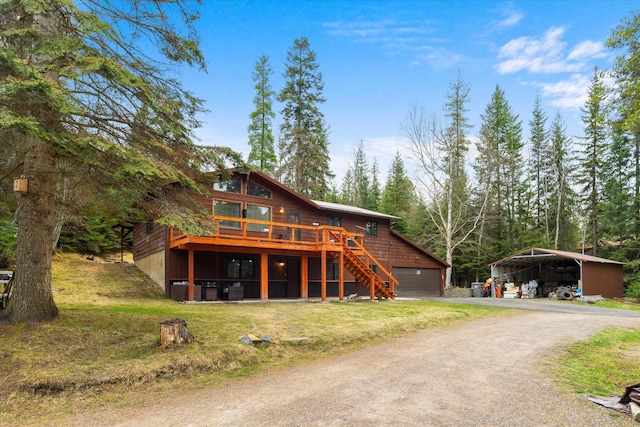 exterior space with a detached carport, stairway, driveway, a wooden deck, and a yard