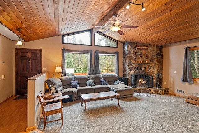 living area featuring a stone fireplace, vaulted ceiling, visible vents, ceiling fan, and wood ceiling