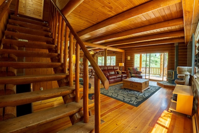 5228 Sophie Lake Rd, Eureka, MT 59917 - living room with a wood stove, wood-type flooring, wooden ceiling with exposed beams, and stairs