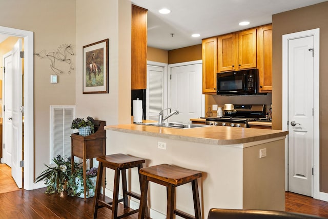 6104 Monterra Ave Unit A, Whitefish, MT 59937 - kitchen with black microwave, stainless steel range, dark wood-style flooring, a breakfast bar, and recessed lighting