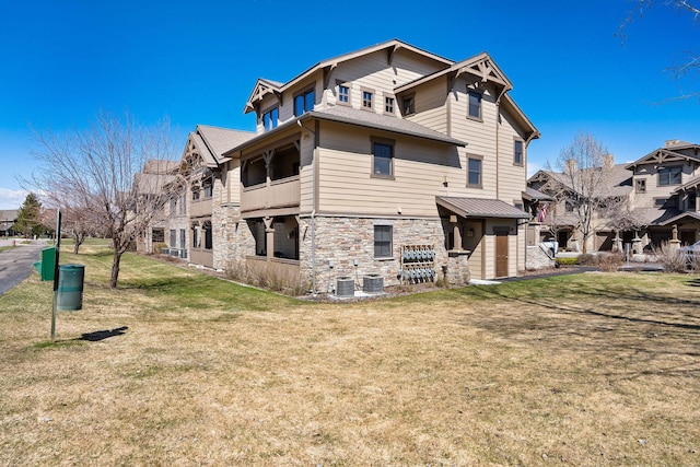 6104 Monterra Ave Unit A, Whitefish, MT 59937 - back of house featuring stone siding, a yard, and a balcony