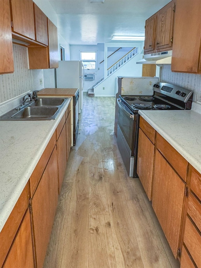 123 W Jefferson Ave, Chester, MT 59522 - kitchen with stainless steel electric range, under cabinet range hood, brown cabinets, light wood finished floors, and light countertops