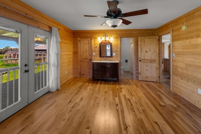 68 Bieler Ln, Sheridan, MT 59749 - unfurnished living room with wood walls, light wood-style flooring, ceiling fan, and french doors